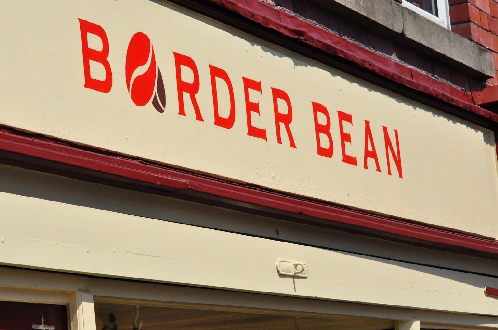 The Border Bean sign: red capital letters on cream, the O drawn as a coffee bean